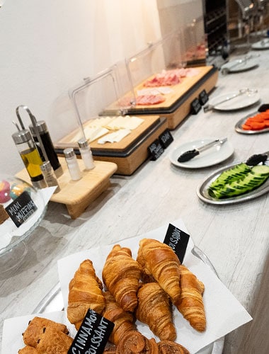 Desayuno buffet en el Hotel Don Carlos con variedad de panes, embutidos y frutas frescas.