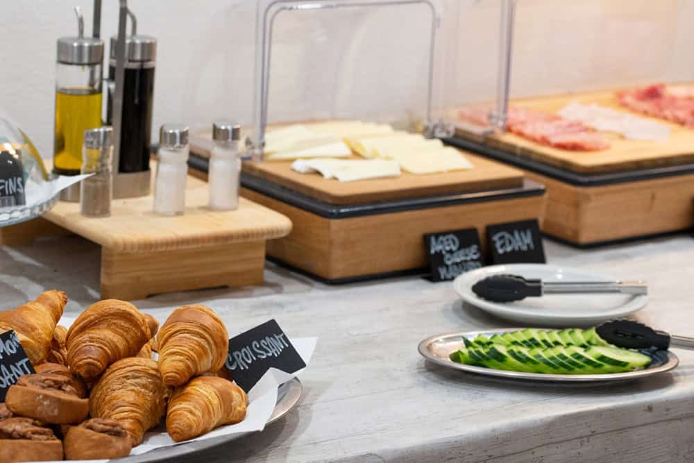 Desayuno con croissants, embutidos y verduras frescas en Hotel Don Carlos.