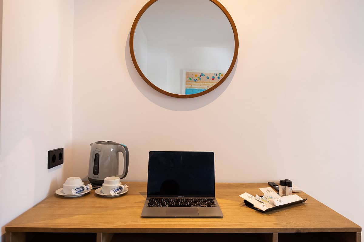 Espacio de trabajo en habitación del Hotel Don Carlos con escritorio, portátil, té, café y espejo re.