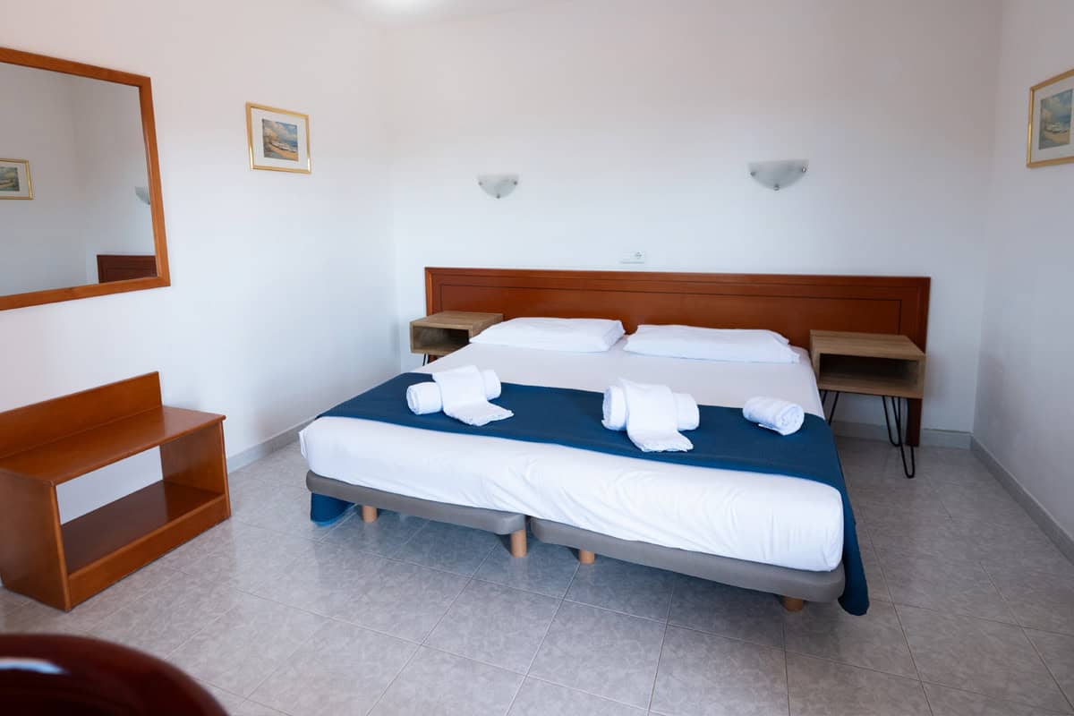 Habitación doble moderna en Hotel Don Carlos, con cama cómoda, ropa de cama blanca y decoración senc.