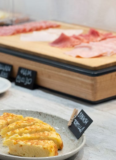Área de comida con embutidos y quesos en Hotel Don Carlos.