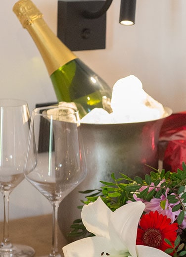 Bote de champagne en hielo con flores y copas para brindar.