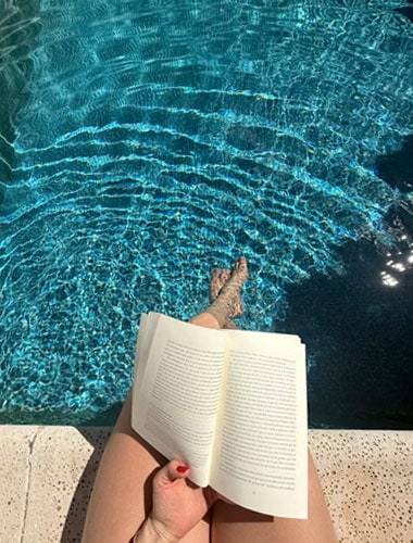 Persona leyendo un libro junto a la piscina en Paguera.